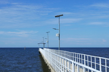 Obraz premium Perspective view of jetty with LED street light with solar cell on clear blue sky.