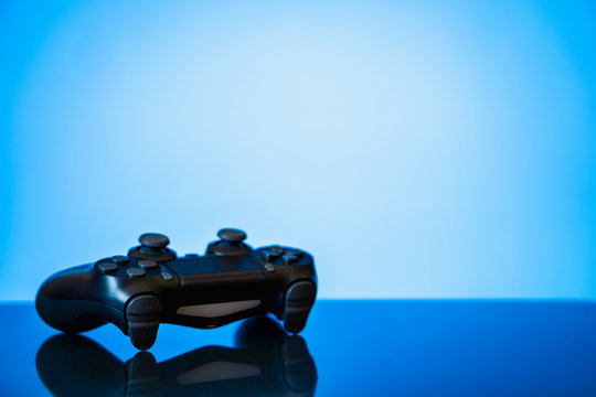 modern black gamepad on a glossy surface and a glowing blue