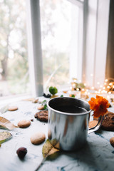 Cup with tea near the window with autumn leaves and cookies