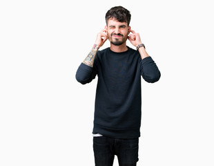 Fototapeta premium Young handsome man over isolated background covering ears with fingers with annoyed expression for the noise of loud music. Deaf concept.