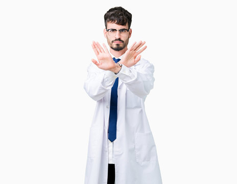 Young professional scientist man wearing white coat over isolated background Rejection expression crossing arms and palms doing negative sign, angry face