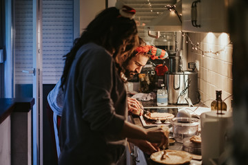 Focused man spreading cream on pancake in the kitchen