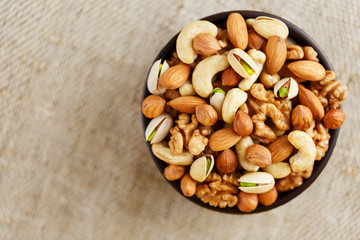 Roasted peanuts in the shell and peeled in a cup, against a gray wooden table
