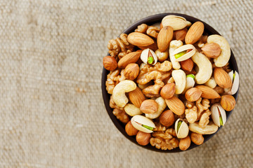 Roasted peanuts in the shell and peeled in a cup, against a gray wooden table