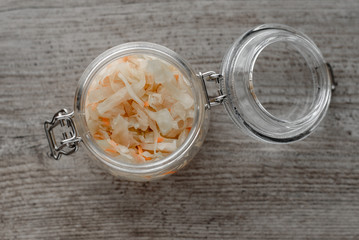 Vitamin cooking, homemade sauerkraut in a glass jar, wooden spoon on a wooden background.
