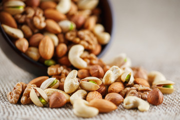 Walnut platter spilled out of the cup on the background of cloth from burlap. Nuts as structure and background, macro.
