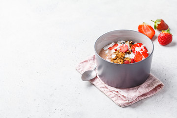 Strawberry smoothie bowl with granola, coconut and berries on a white background.