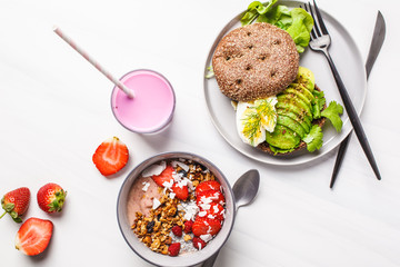Beautiful breakfast: smoothie bowl, avocado toast and dessert on a white marble background, top view. Valentine's Day concept.