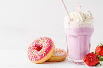 Strawberry milkshake with whipped cream and glazed donut on white background, copy space for text. Valentine's day concept.