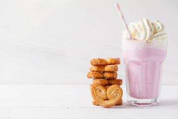 Strawberry milkshake with whipped cream and cookies Palmiers on white background, copy space for text. Valentine's day concept.