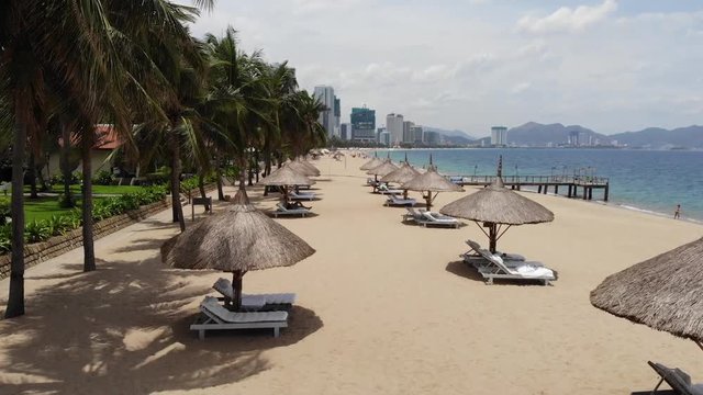 A flying camera over the beach of Nha Trang Vietnam sea island of palm trees and the city. Move from left to right upwards and downwards.