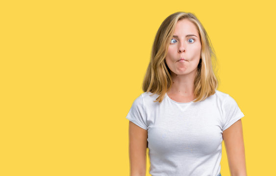 Beautiful young woman wearing casual white t-shirt over isolated background making fish face with lips, crazy and comical gesture. Funny expression.
