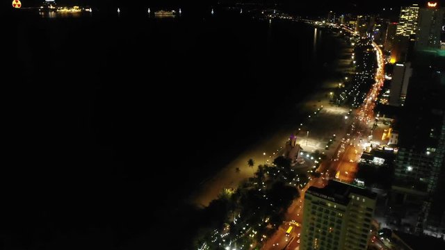 Flying camera flies over the night road and the roof of a skyscraper in Nha Trang Vietnam shot from a drone.