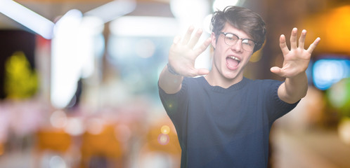 Young handsome man wearing glasses over isolated background showing and pointing up with fingers number nine while smiling confident and happy.