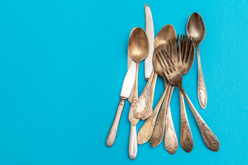 old darkened forks spoons and knives on blue background