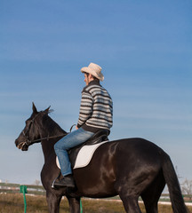 Man riding horse, striped pullover, blue jeans, hat, close up