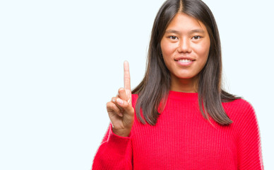 Young asian woman wearing winter sweater over isolated background showing and pointing up with finger number one while smiling confident and happy.