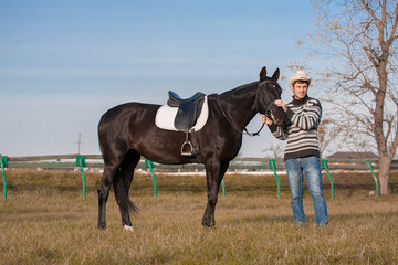 Man nearby horse, striped pullover, blue jeans, hat, landscape