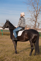 Man riding horse, striped pullover, blue jeans, hat, landscape