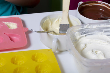 A woman using a brush brushes a melted chocolate silicone mold for dessert.