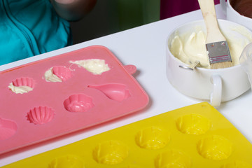 A woman using a brush brushes a melted chocolate silicone mold for dessert.