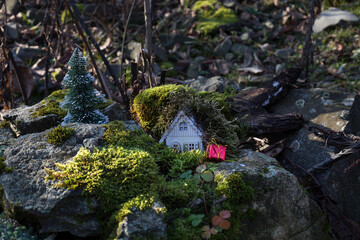 Christmas and New Year miniature house at forest in the sunlight. Little toy house close up. Festive background. Christmas decorations. Holiday and celebration concept.