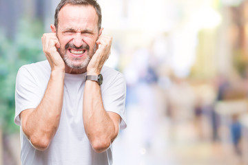 Middle age hoary senior man wearing white t-shirt over isolated background covering ears with...