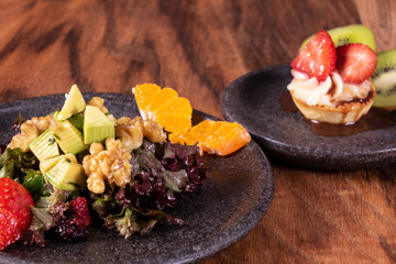 Green salad with Fruit and berry tart dessert with kiwi and strawberry with blood oranges, alligator pear, beets, seeds and nuts on a wooden background, selective focus, free space.
