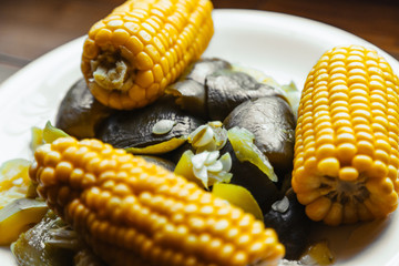 Macro close-up of boiled corn and vegetables on a white plate with focus on vegetables