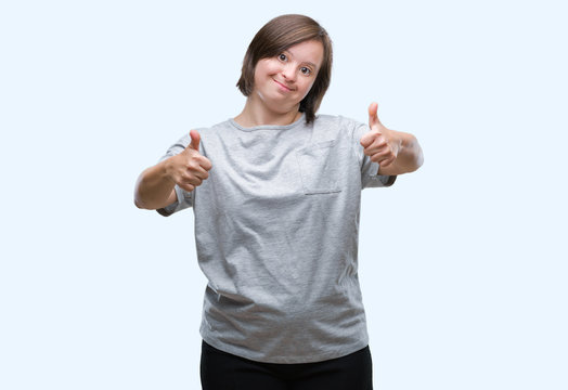 Young adult woman with down syndrome over isolated background success sign doing positive gesture with hand, thumbs up smiling and happy. Looking at the camera with cheerful expression