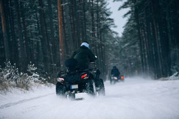 Rider driving in the quadbike in winter in the forest 