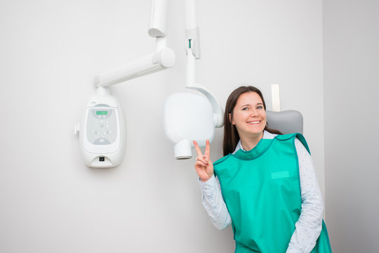 Joyful beautiful woman in the dental clinic is preparing for an X-ray. Diagnostics in dentistry