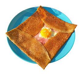 Crepe complet on blue plate isolated on white background - traditional breton meal: pancake from...