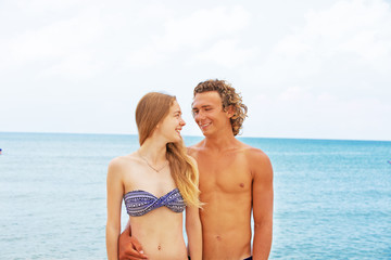 Fototapeta premium Portrait of young couple in love at beach and enjoying time being together. Young couple having fun on a sandy coast.