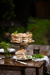 Delicious cake on a high tray. Tea drinking after rain in nature. copy space