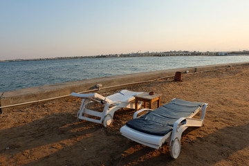 Two loungers on the shore of the Red Sea with a view of the hotel in the background.