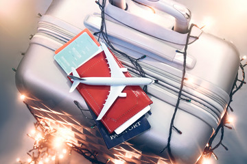 Idea for tourism with an airplane, a passport and tickets on a suitcase with bright garlands. Concept on the theme of New Year and holiday flights. © vadish