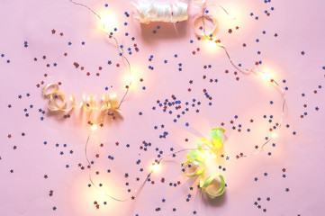 Festive garland of small light bulbs and stars on pink pastel tr