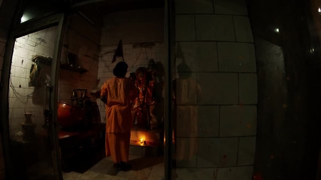 Hindu monk performs Aarti does circulate motions with burning light fixture around statue of Hanuman monkey God