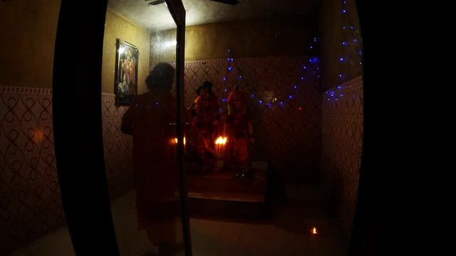 Hindu monk performs evening aarti to Krishna's and Rukmini's statues rings bell and repeats movements with burning light fixture