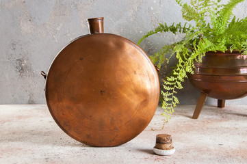 Antique copper flask on concrete background.