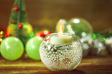 Fototapeta na wymiar Christmas glass spherical candlestick and candle on the background of new year decorations.