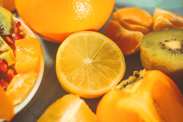 Fototapeta na wymiar cut scitrus fruits. orange, pomegranate, mandarin, persimmon, kiwi. on a blue wooden board.