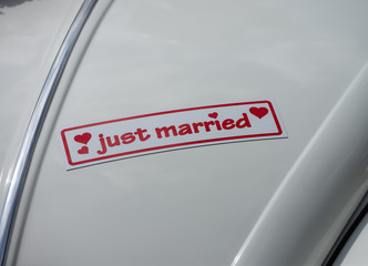 Magnettafel mit der Aufschrift Just Married auf der Kühlerhaube eines Autos bei einer Hochzeit