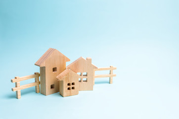Wooden houses on a blue background. Wooden Toys. The concept of real estate and ownership, the purchase and sale of property. Farm, city, village, enterprise. Construction and improvement of buildings