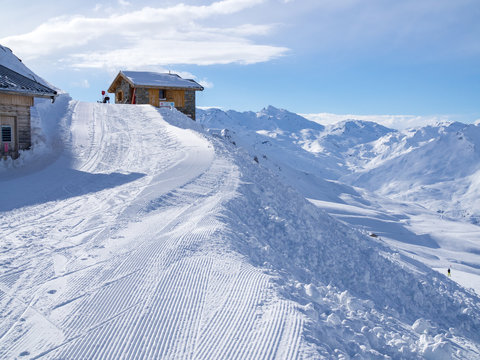 Meribel, France - February, 2018: Wooden Houses in Meribel ski resort. Skiers and snow slopes, beautiful sunny day.