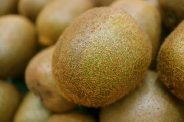 Closed Up Fresh Kiwi Fruit on blurry Kiwi Fruits Pile