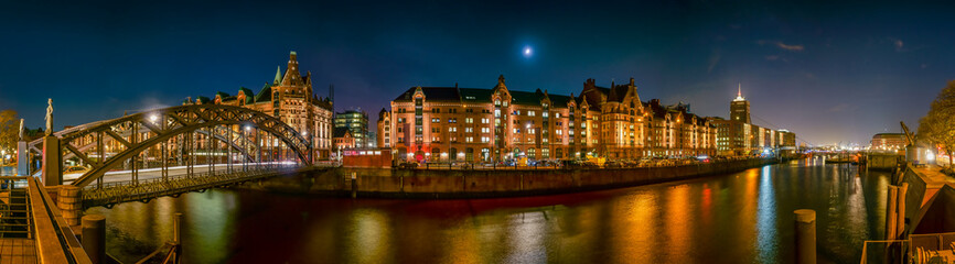 The Warehouse District (Speicherstadt) in Hamburg, Germany, at night. The panoramic view is across...