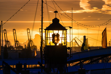 Hamburg Harbor, Germany, at sundown with silhouettes of cranes and the top of a historic lightship.