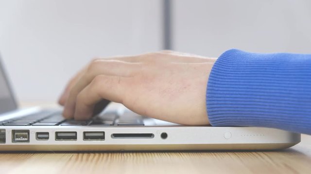 Close-up - male hands are typing message on a laptop